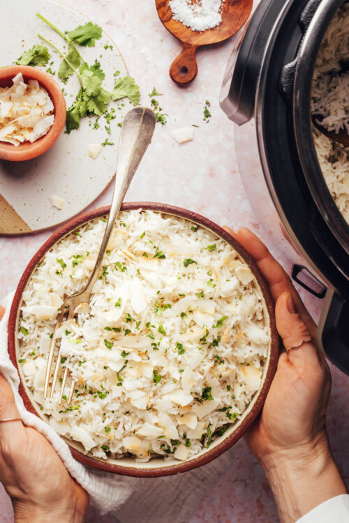 Hands holding a bowl of coconut rice made in the Instant Pot