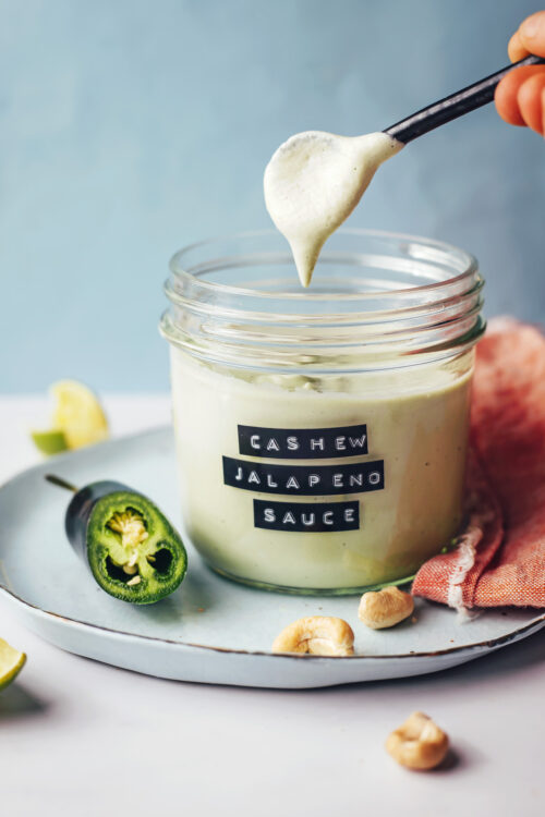 Spoon and glass jar of our creamy vegan cashew jalapeño sauce