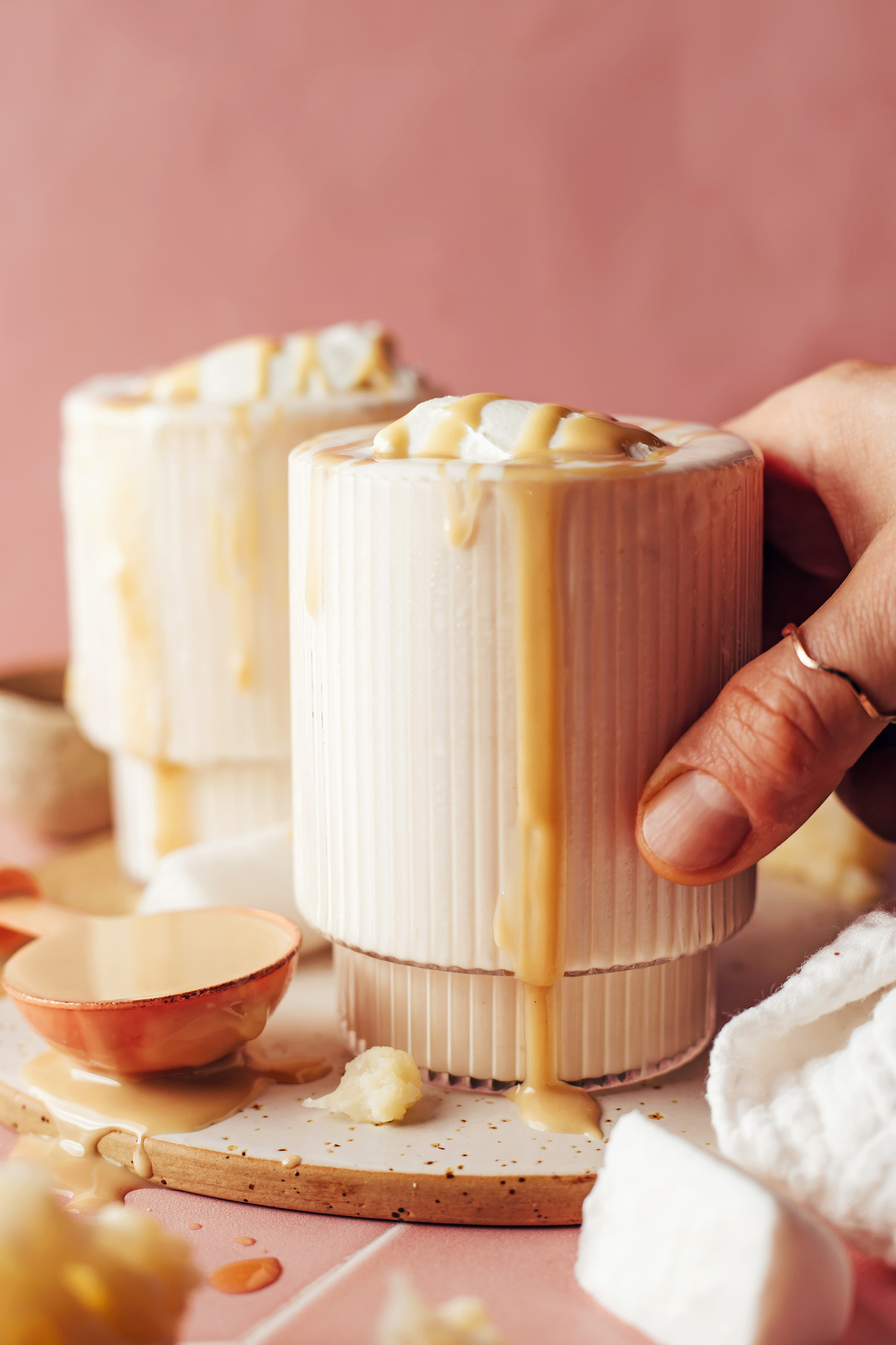 Holding a glass of a vanilla tahini shake with tahini dripping down the side