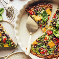 Overhead shot of a partially sliced quiche with veggies