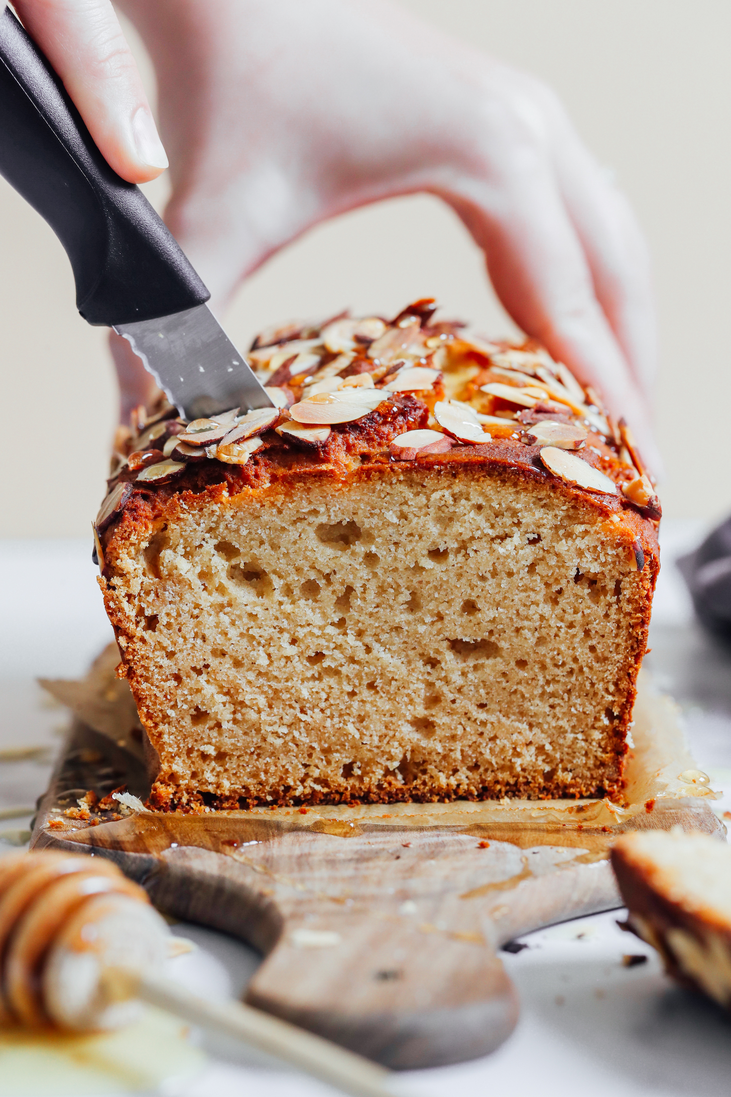 Slicing into a loaf of gluten-free honey almond snack cake