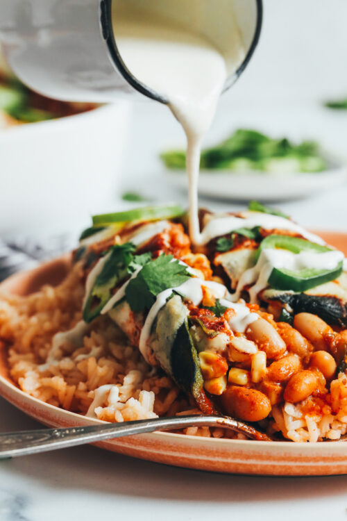 Drizzling cashew cream over a baked vegan chile relleno