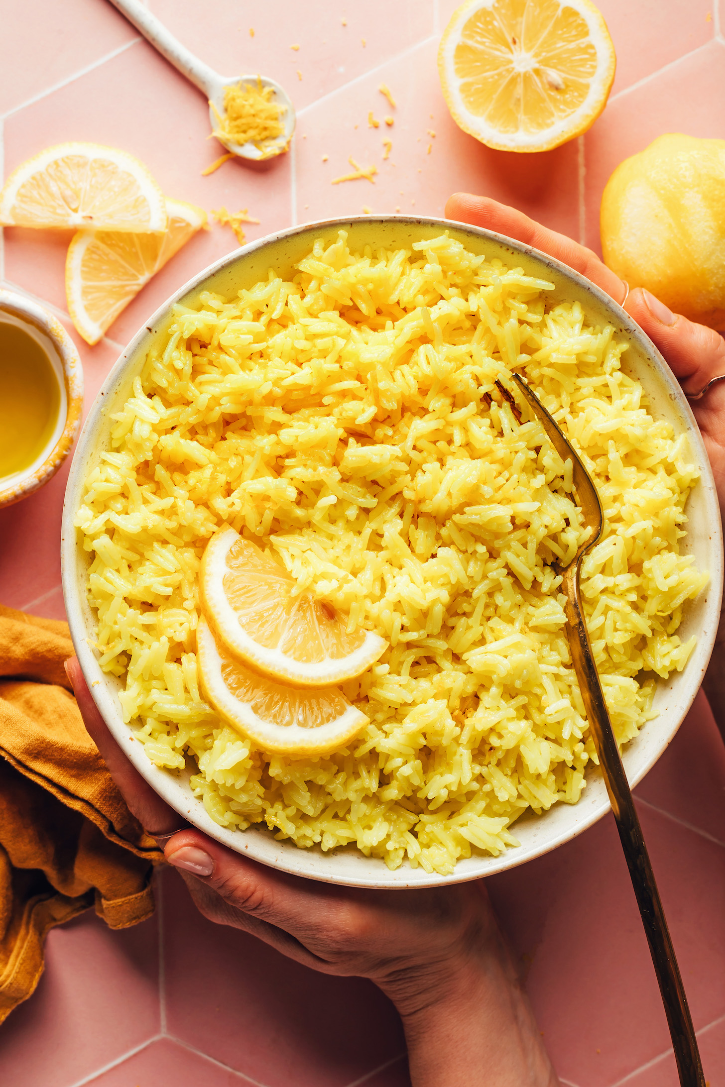 Hands holding the sides of a bowl of Greek lemon rice