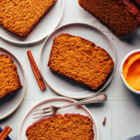 Slices of our gluten-free pumpkin bread on plates next to a half loaf