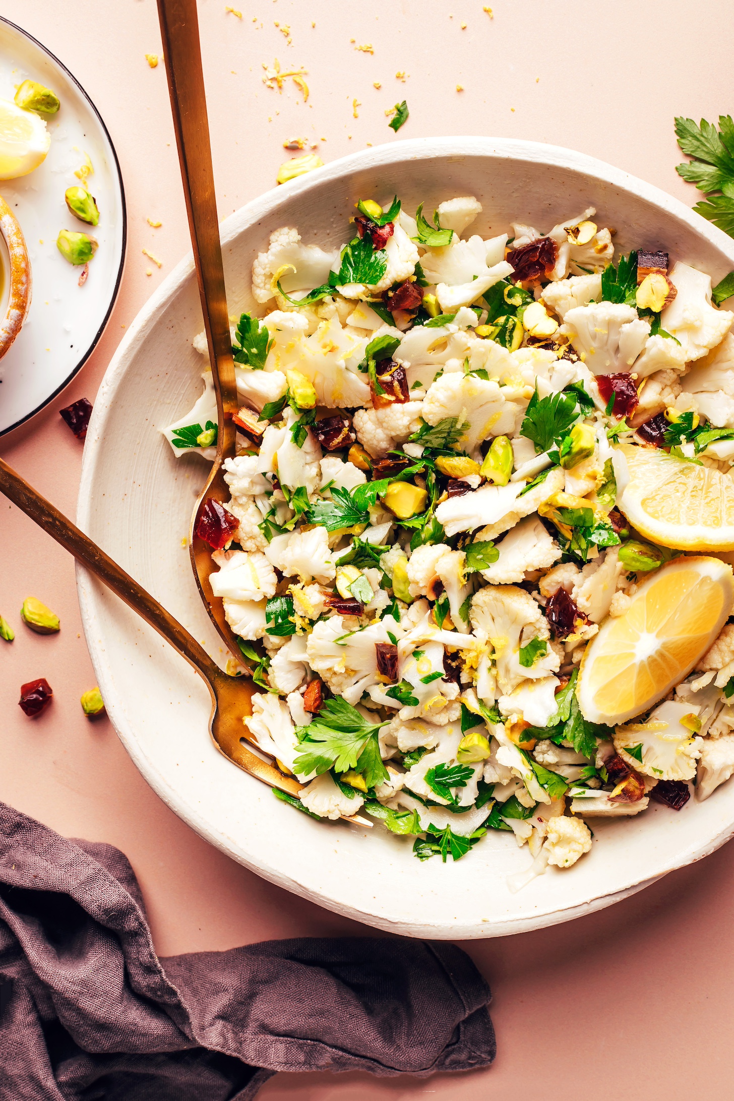 Fork and spoon resting in a bowl of our raw chopped cauliflower salad recipe