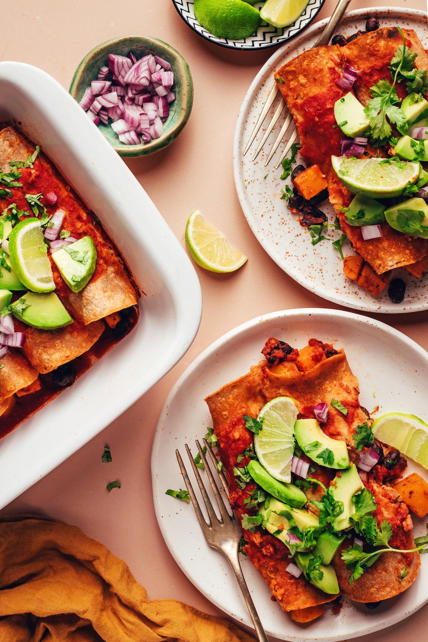 Plates and baking dish of our vegan butternut squash and black bean enchiladas