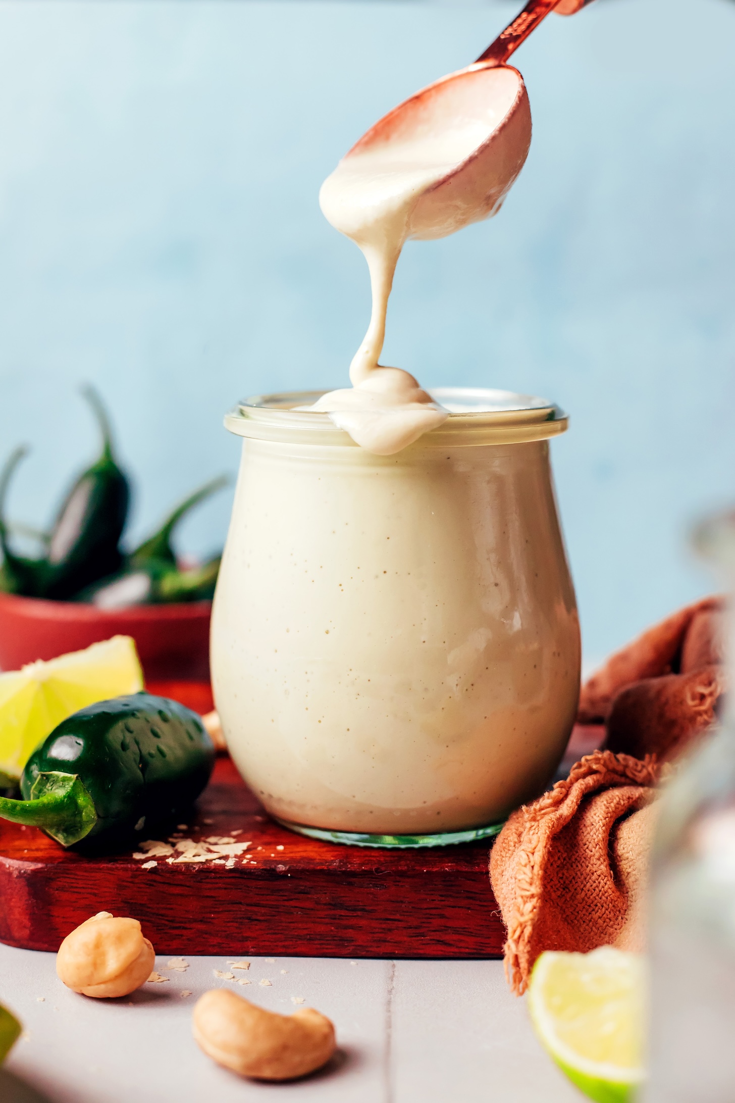 Creamy vegan cashew jalapeño dressing dripping off a spoon into a glass jar