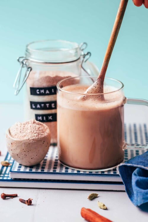Stirring our Instant Chai Latte Mix in a glass with hot water and sweetener